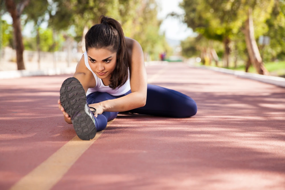 A girl in sports equipment does stretching on treadmills