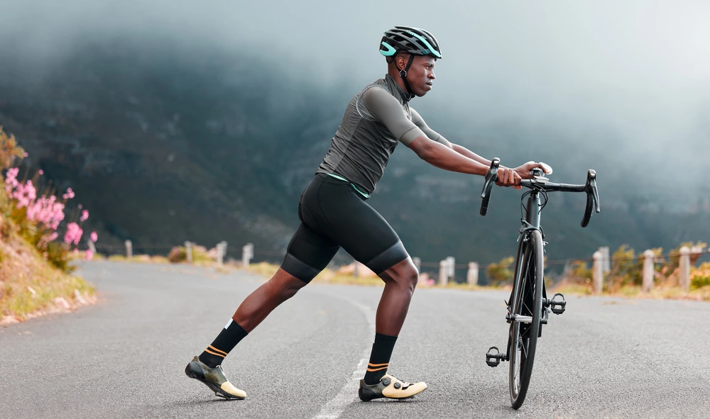 A man in sportswear leans on a bicycle