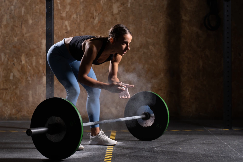 A girl in sports equipment is preparing to lift the barbell